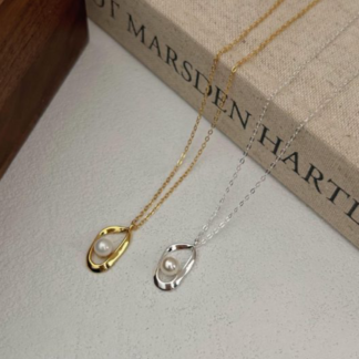 Colar em prata 925 com pendente irregular em gota aberta que abraça uma pérola solta. Dourado ou prateado.