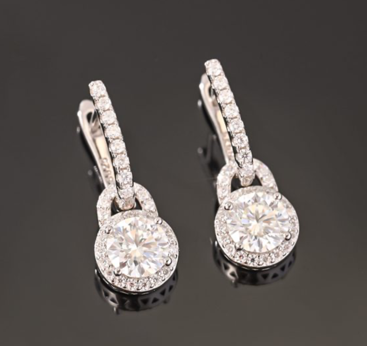 Brincos pendentes em prata 925 com moissanite central e halo de pedras, suspensos de barra em pavé. Elegantes.
