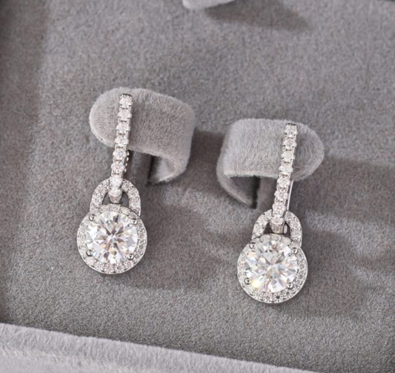 Brincos pendentes em prata 925 com moissanite central e halo de pedras, suspensos de barra em pavé. Elegantes.